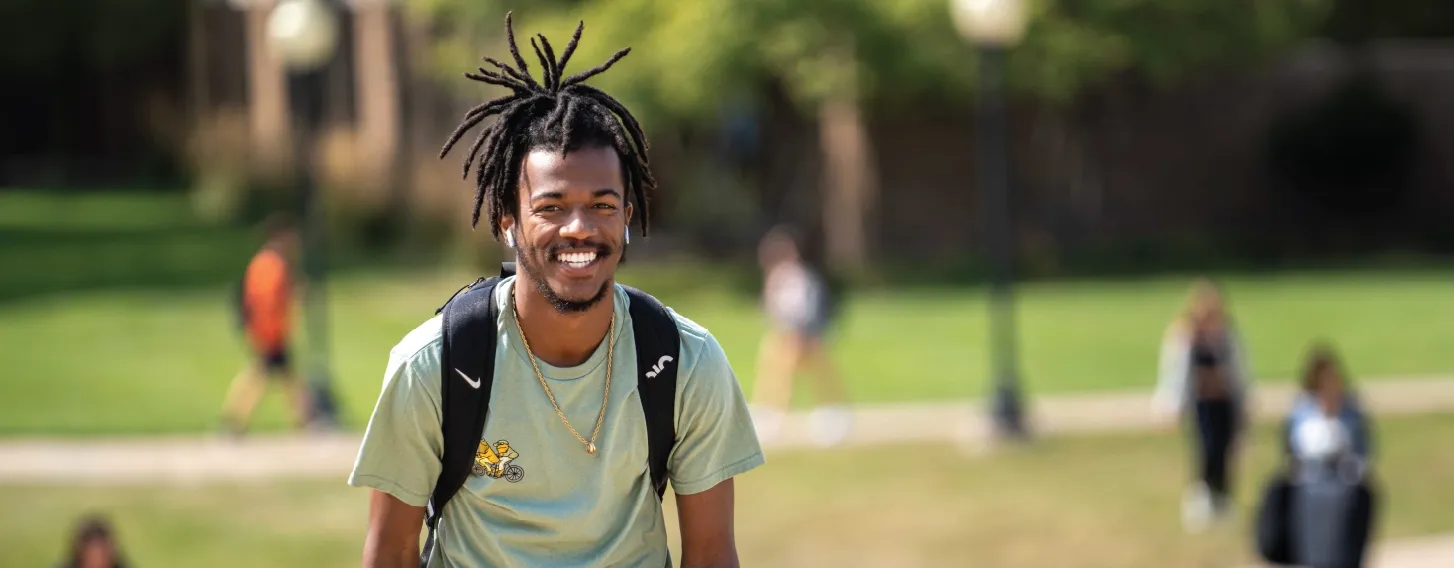 One student smiling outdoors while walking.